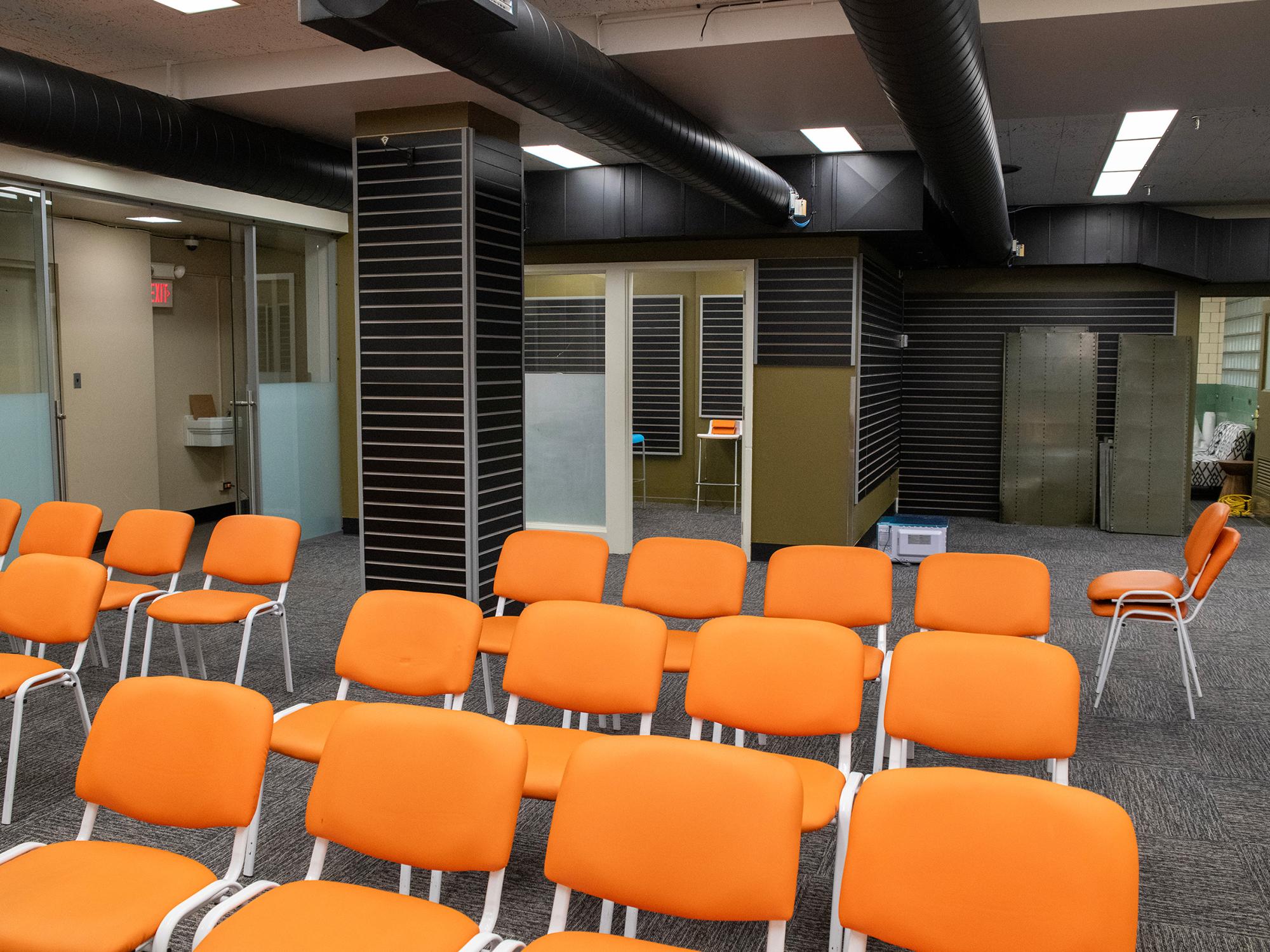 Rows of orange chairs are arranged in an open meeting area within the Mon Valley LaunchBox, surrounded by offices and collaborative workspaces.