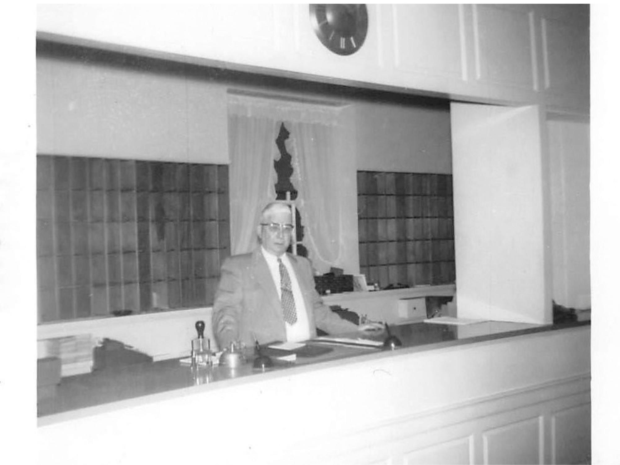 person stands behind hotel desk in the 1950s