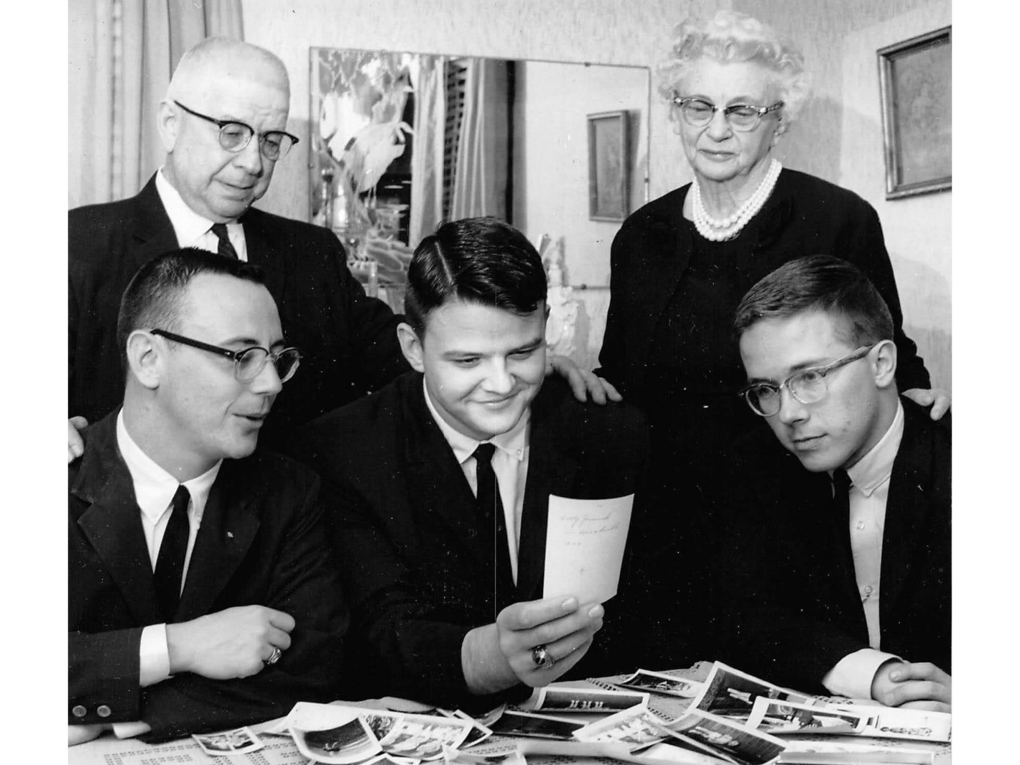 five adults in the 1960s look through a pile of photos