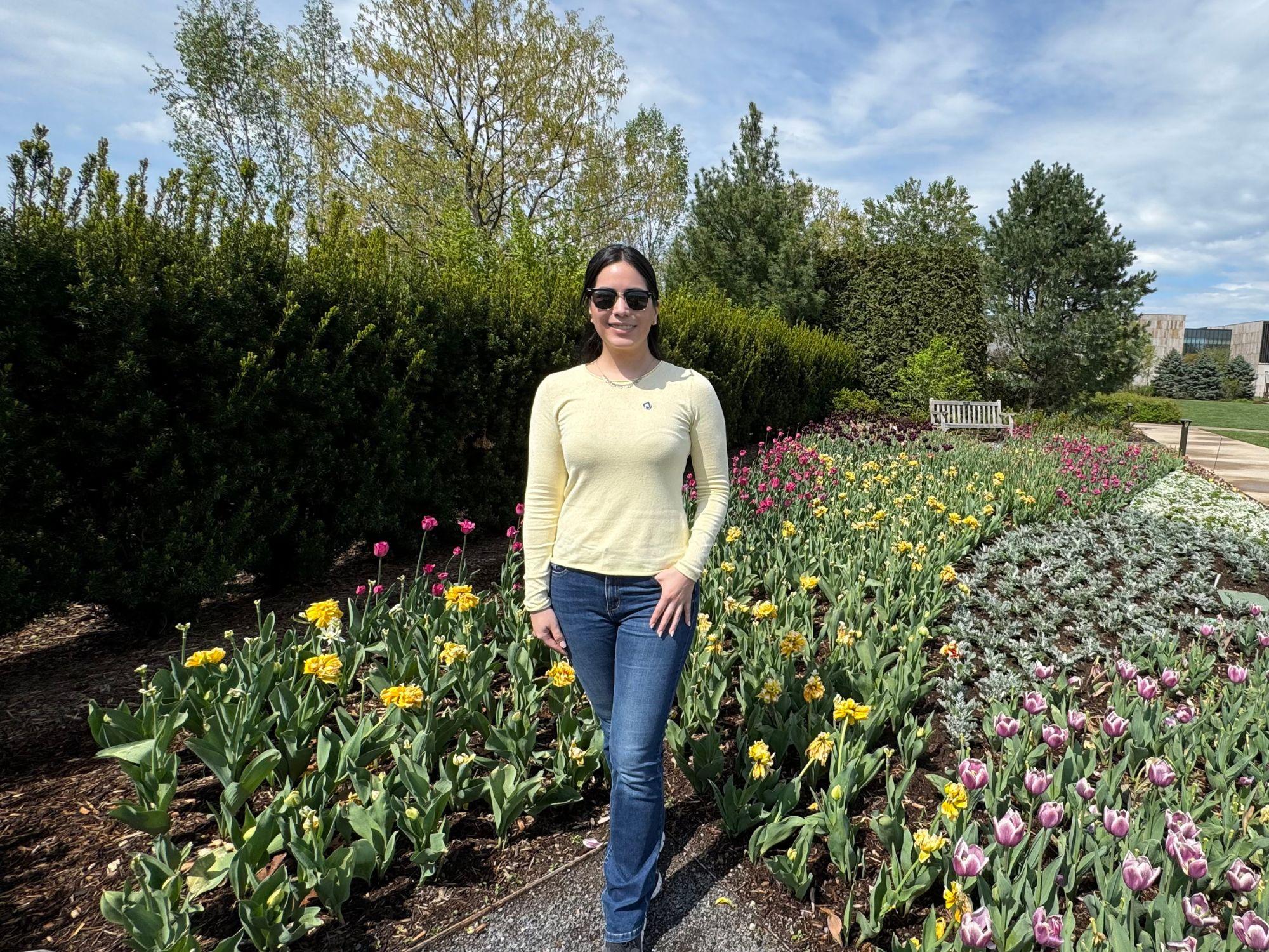 A woman poses for a photo in a garden.