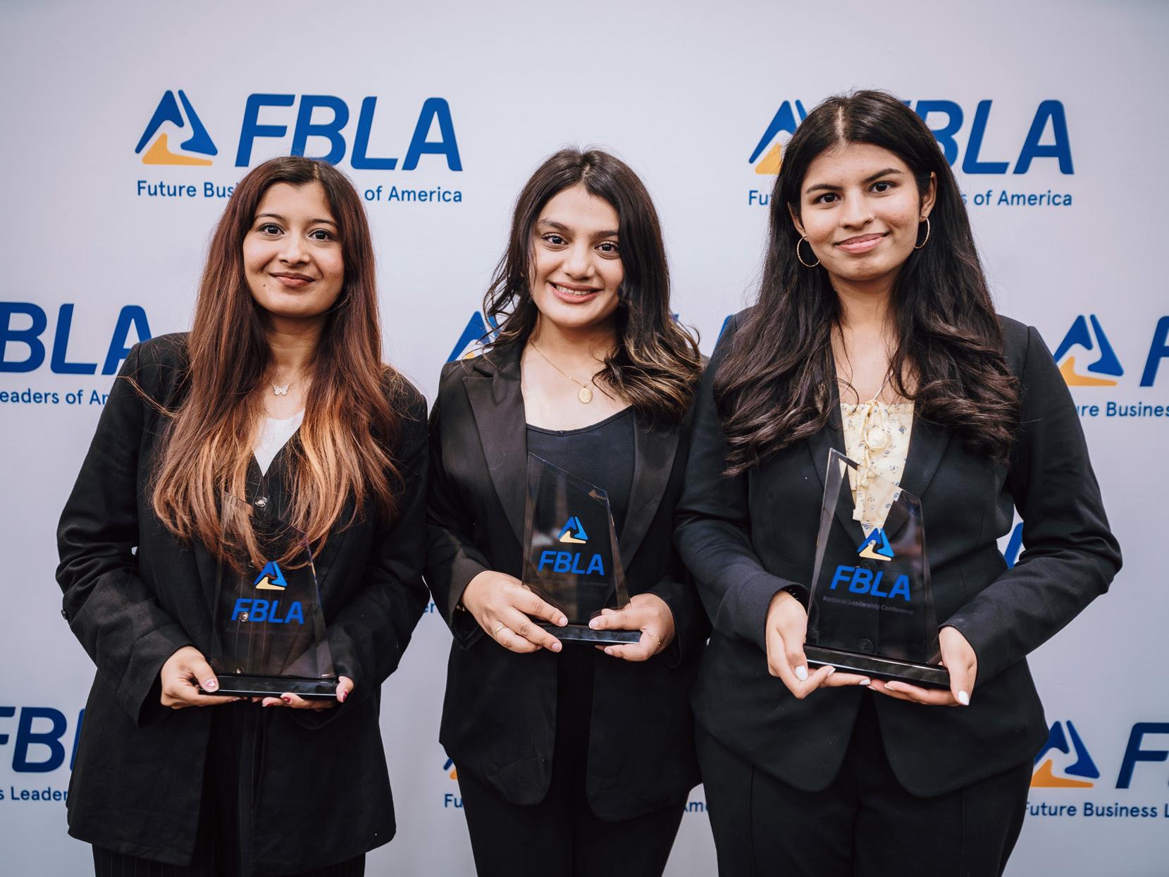 Three Penn State Harrisburg students in business attire hold awards at the FBLA Collegiate National Leadership Conference