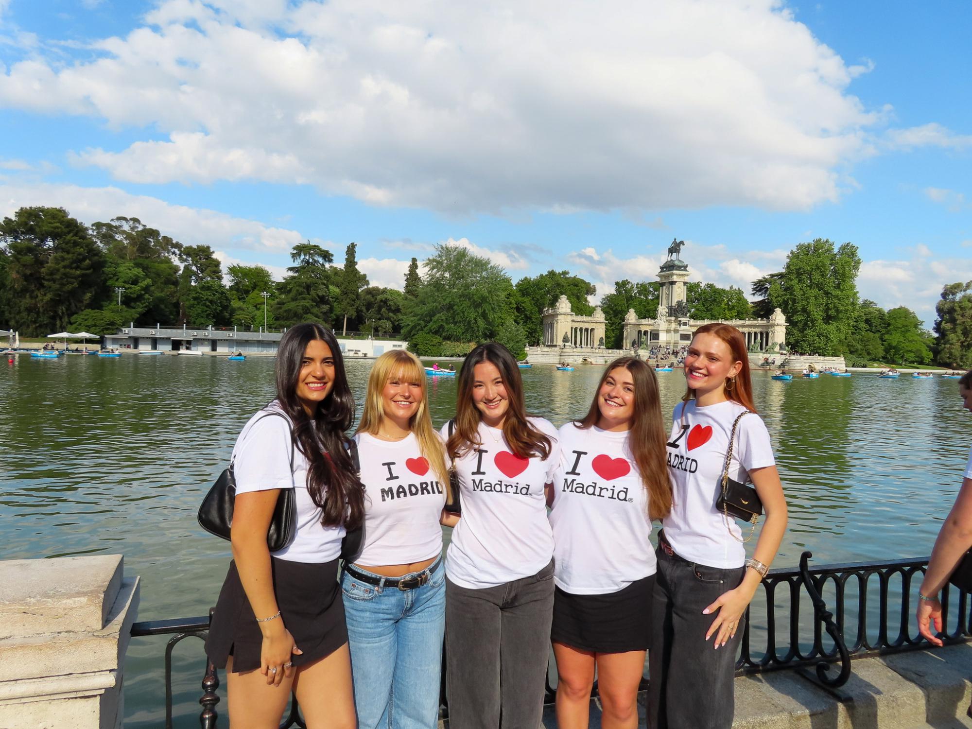 A group of five people stand together in front of a large pond wearing “I Heart Madrid” T-shirts.