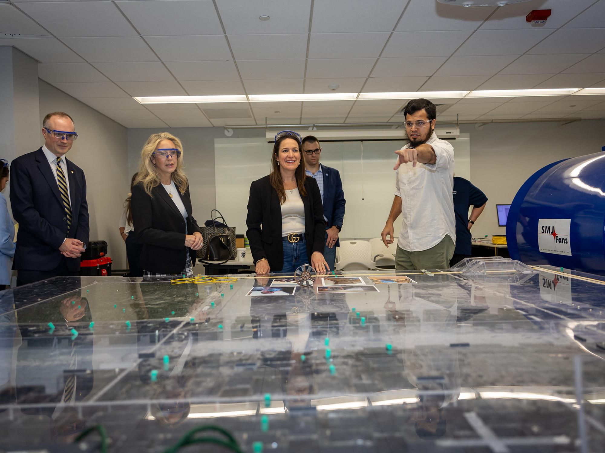 A small group of people look over a mine ventilation model that's used to teach students how to design mine ventilation