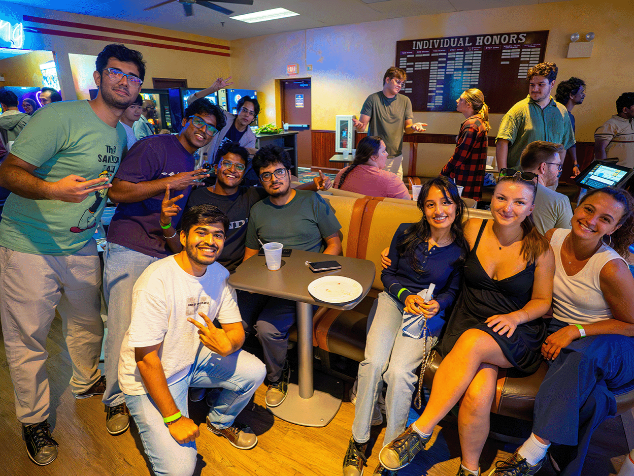 A group of graduate students smiling for a photo at a bowling alley