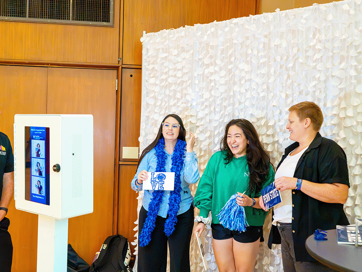 Students pose at a photo booth, holding props and smiling