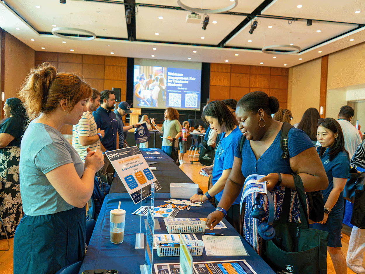 A graduate speaking to a University resource table in Alumni Hall, HUB
