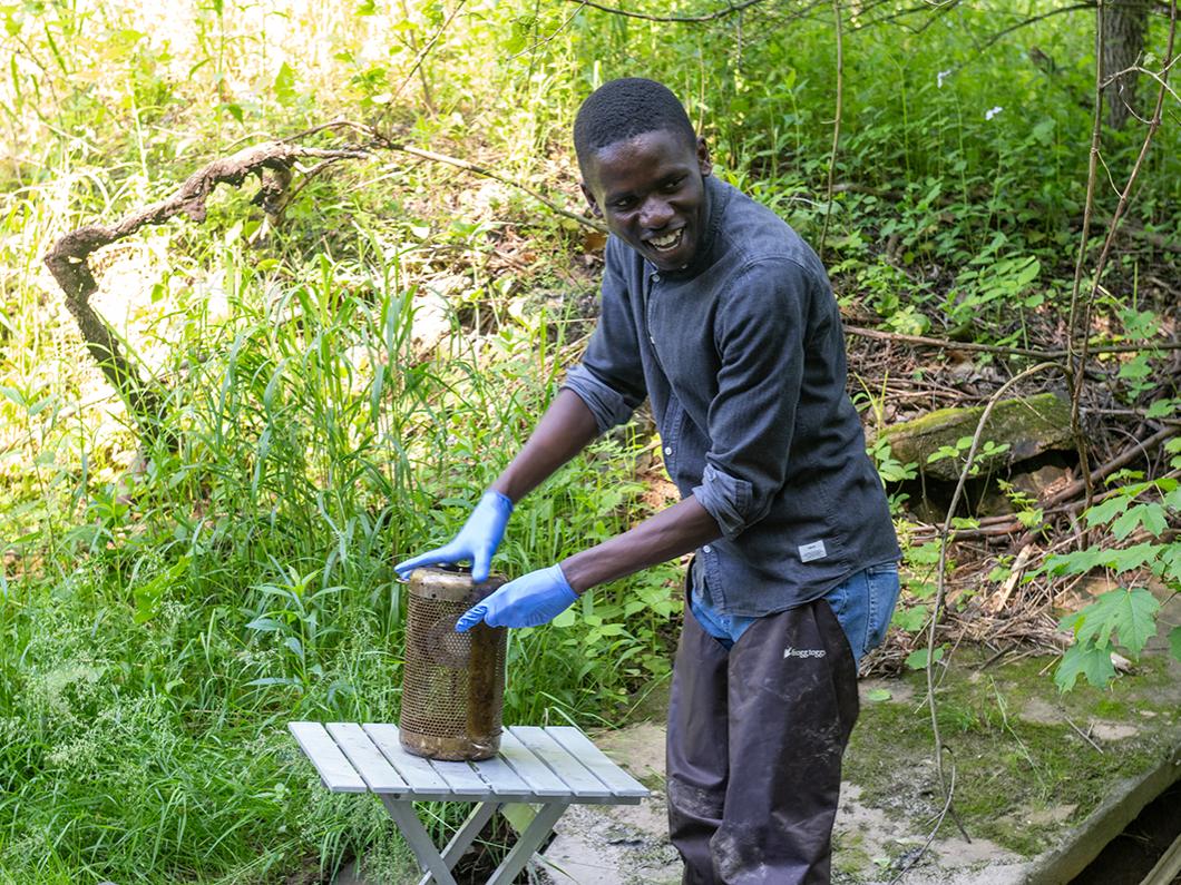 Person standing in a stream holding a sampling container laughs