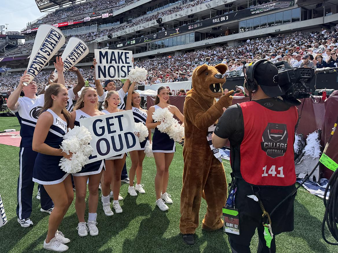 Mascot and cheerleaders mug for TV camera