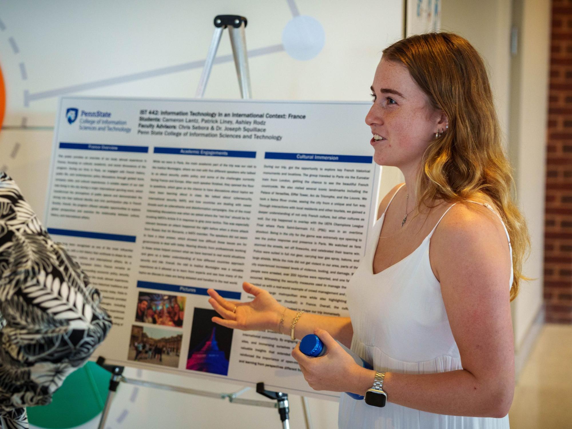 person with long hair and white dress explains poster