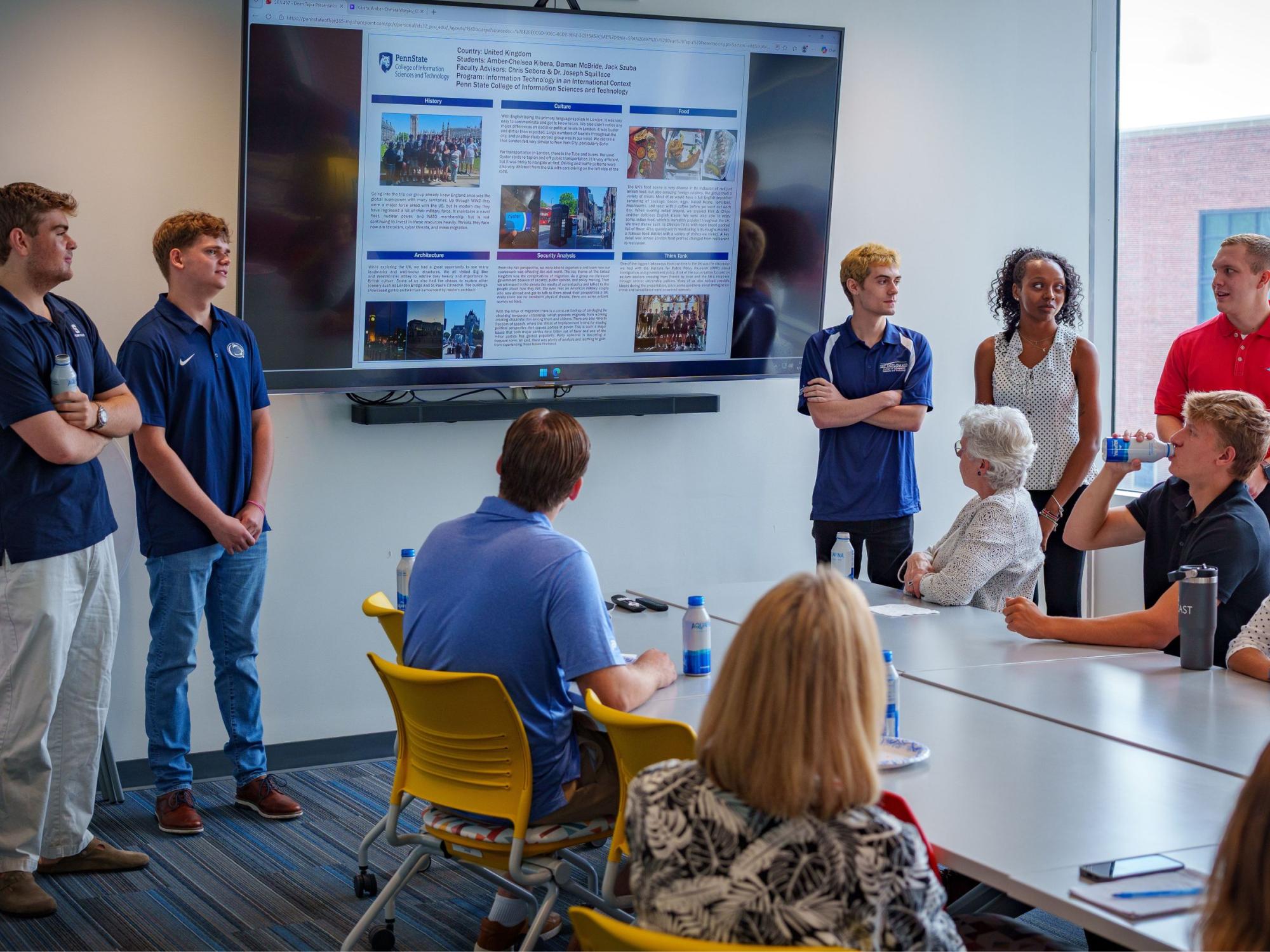 students share power point presentation in colorful college classroom