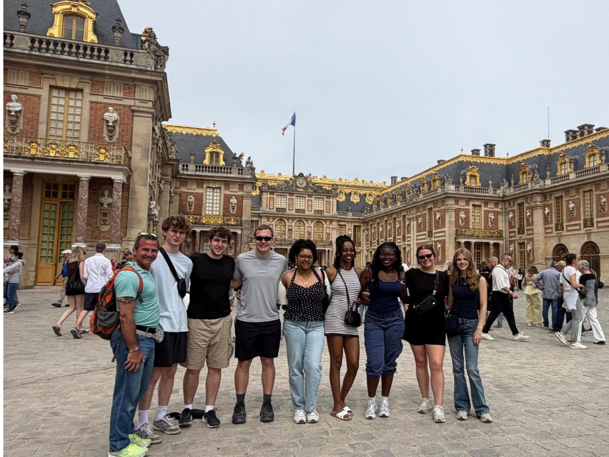 college students pose in front of the Palace of Versailles