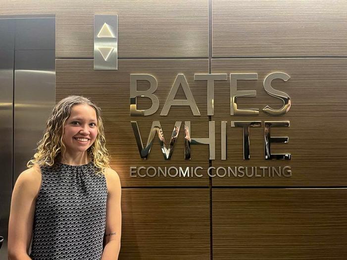 Sonia Lloyd stands in front of a Bates White Economic Consulting sign while visiting the firm in Washington, D.C. 