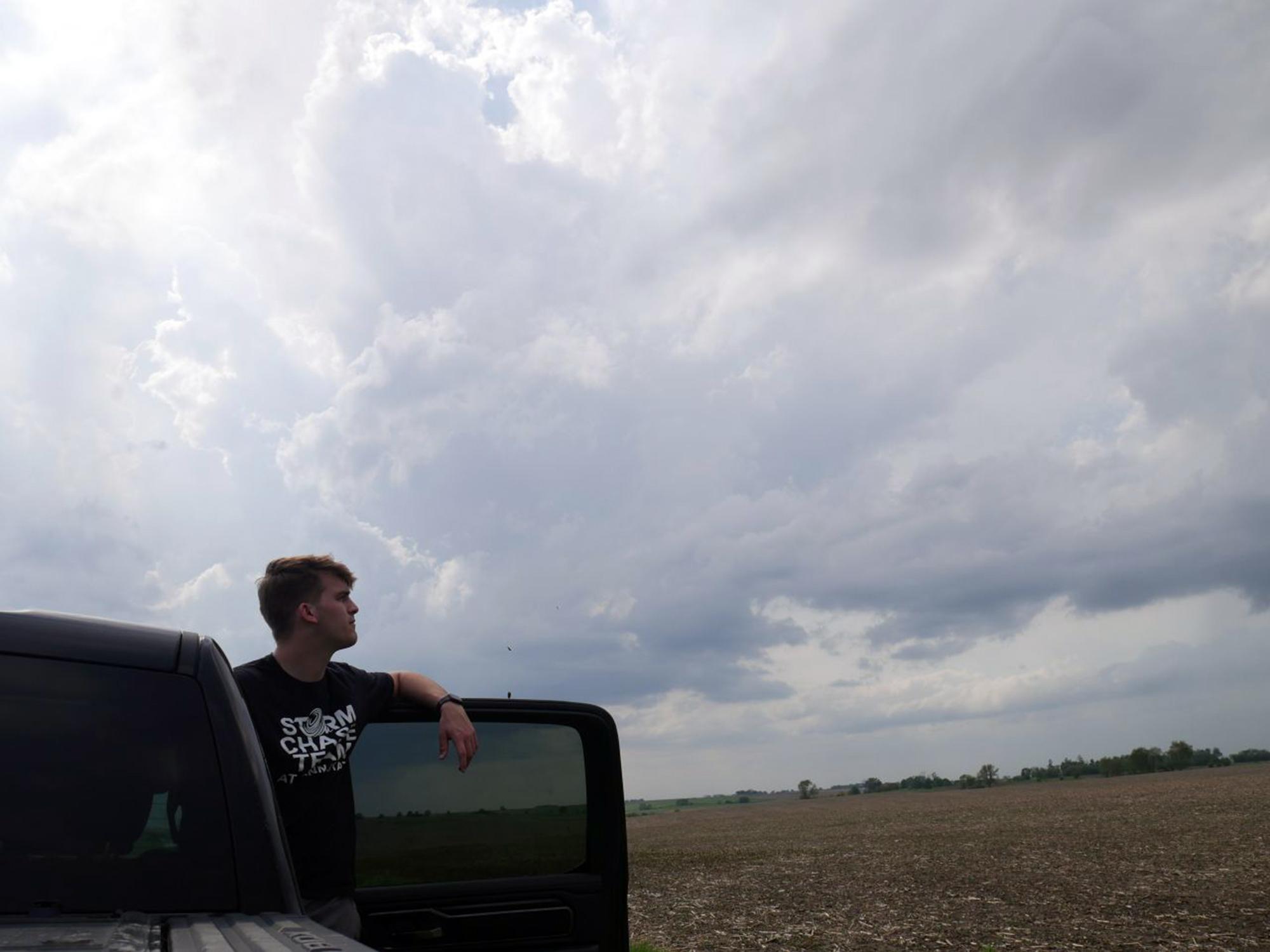 A student looks out of a truck at a nearby storm
