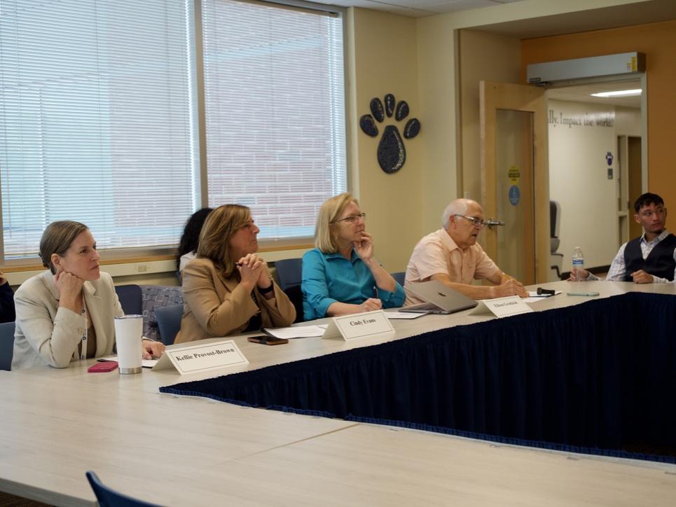 four people sitting at a table watching a presentation