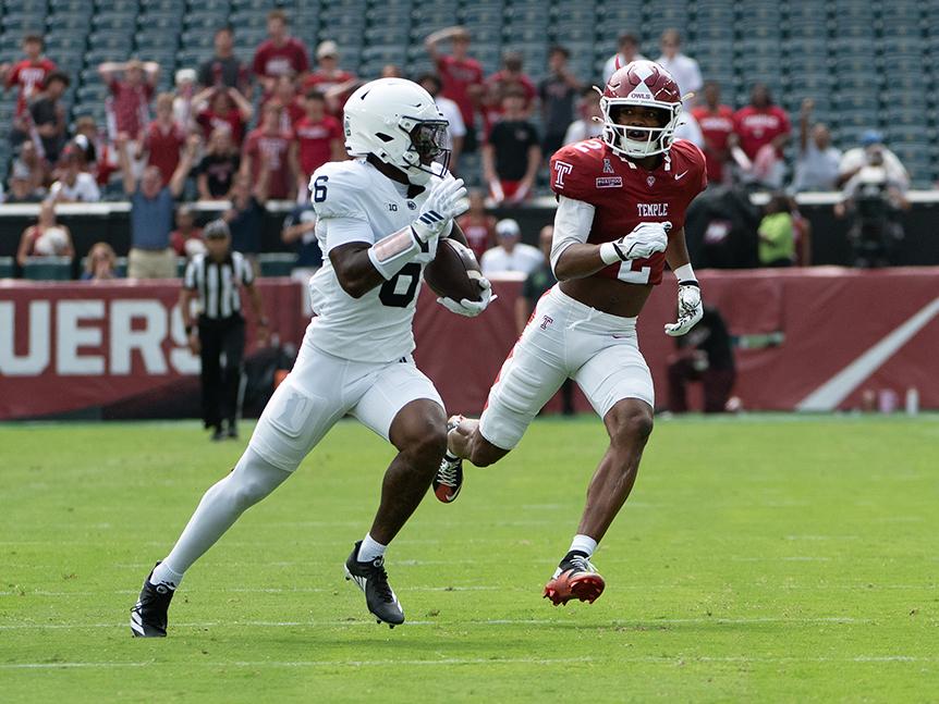 Penn State player running with ball and chased by Temple defender