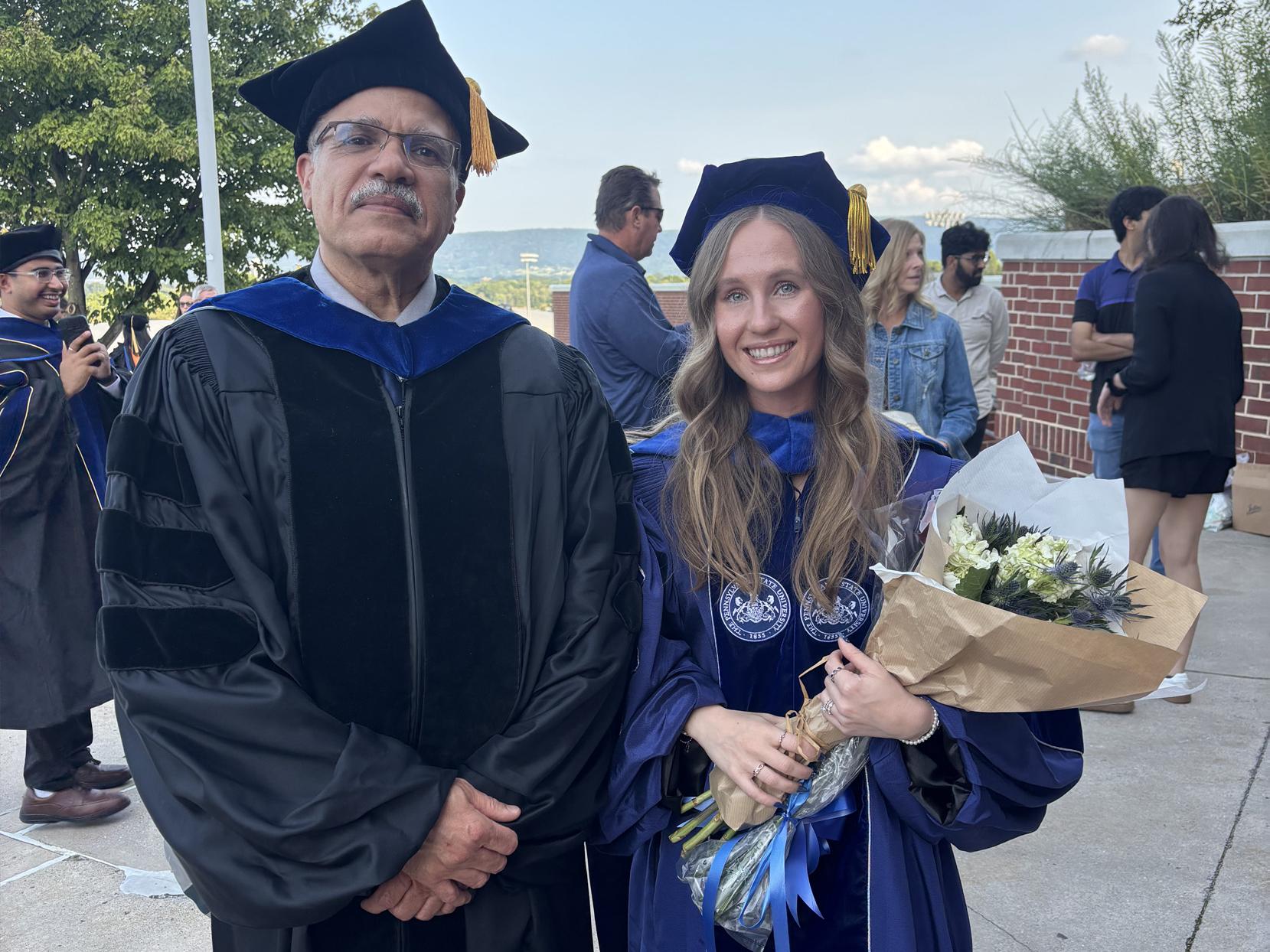 Trisha Campanaro holds flowers and poses for a photo with her adviser Issam Abu-Mahfouz after graduation
