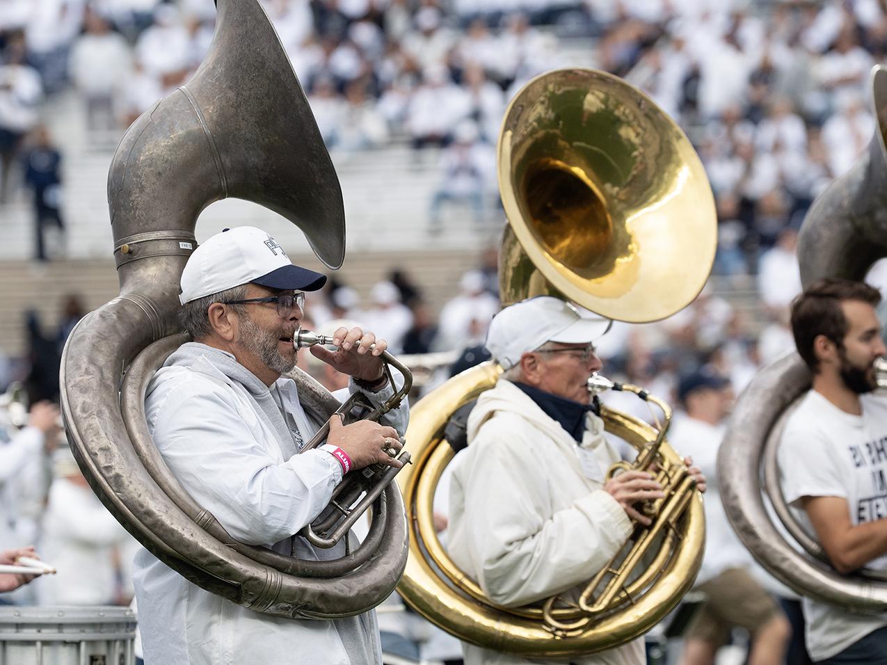 Two alums blowing on tubas