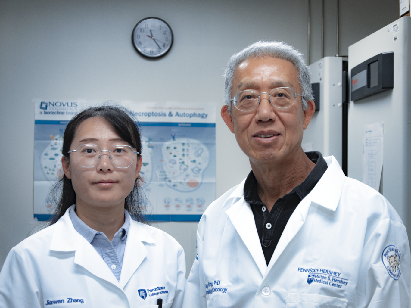 two people in lab coats pose for portrait in laboratory