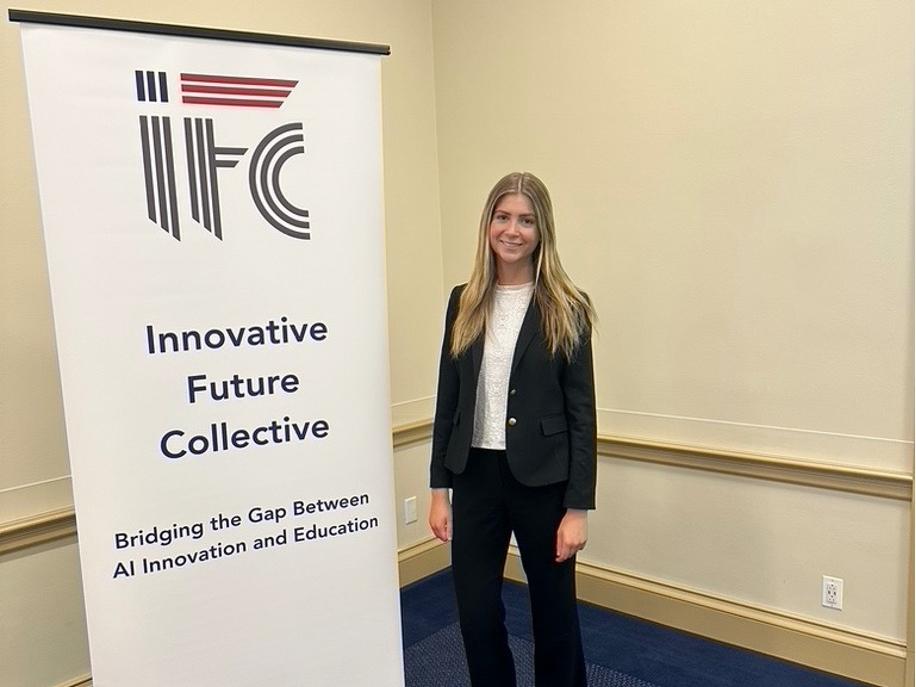 Erin Gregorian in business attire standing next to a banner for Innovative Future Collective about AI innovation and education.