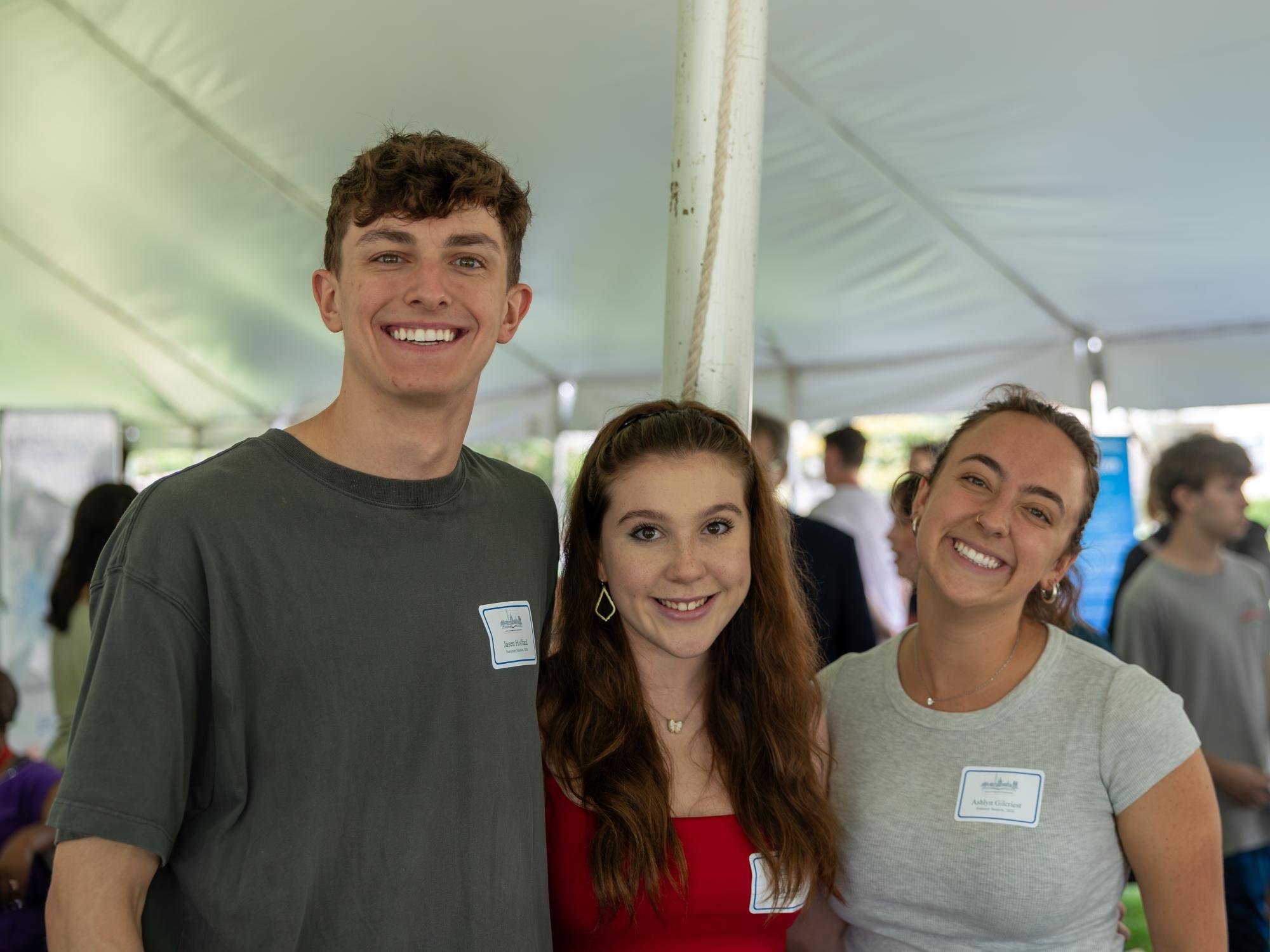 Three students under a tent at the Liberal Arts Undergraduate Festival.