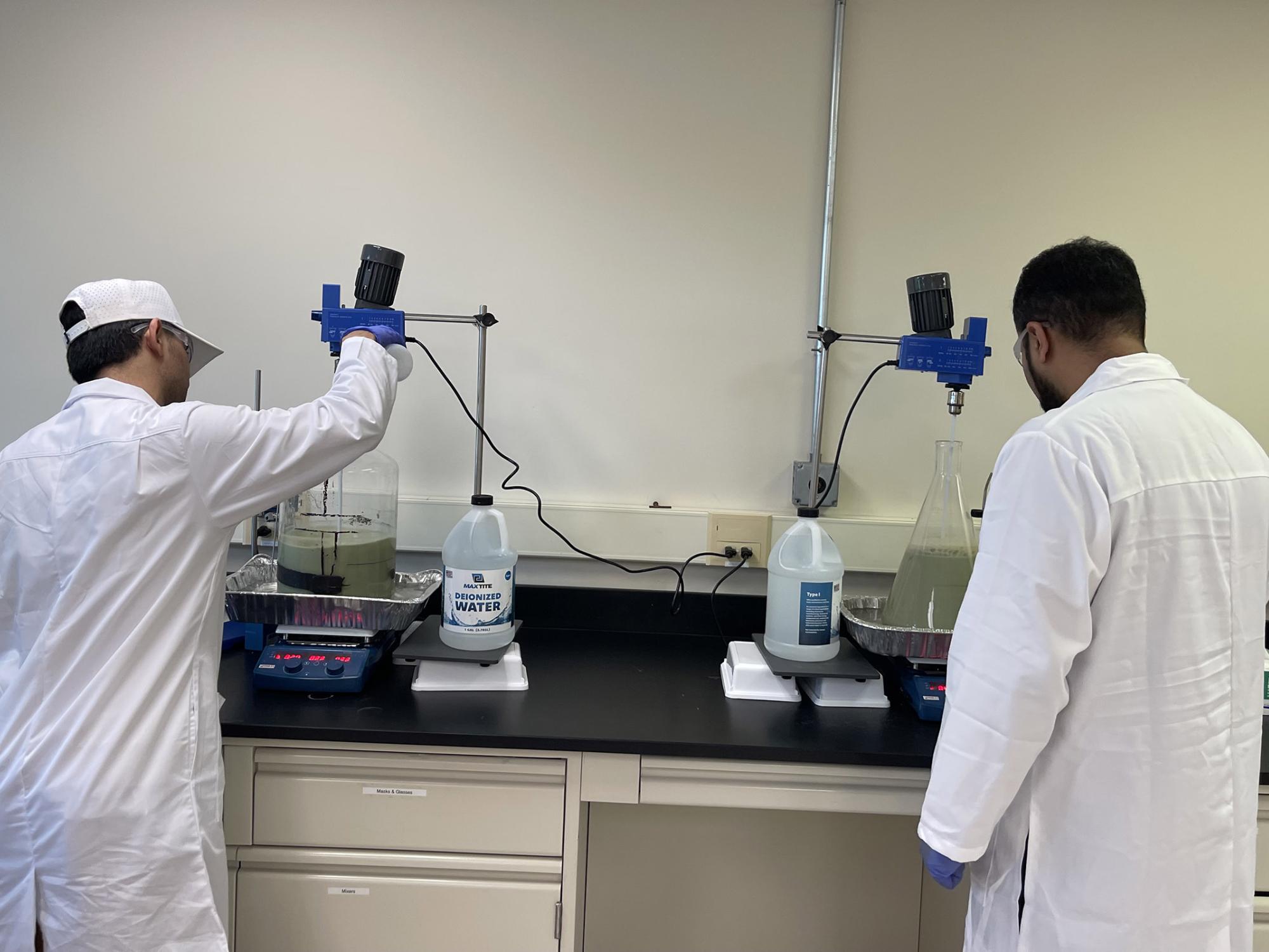 researchers in a lab stand by a lab bench