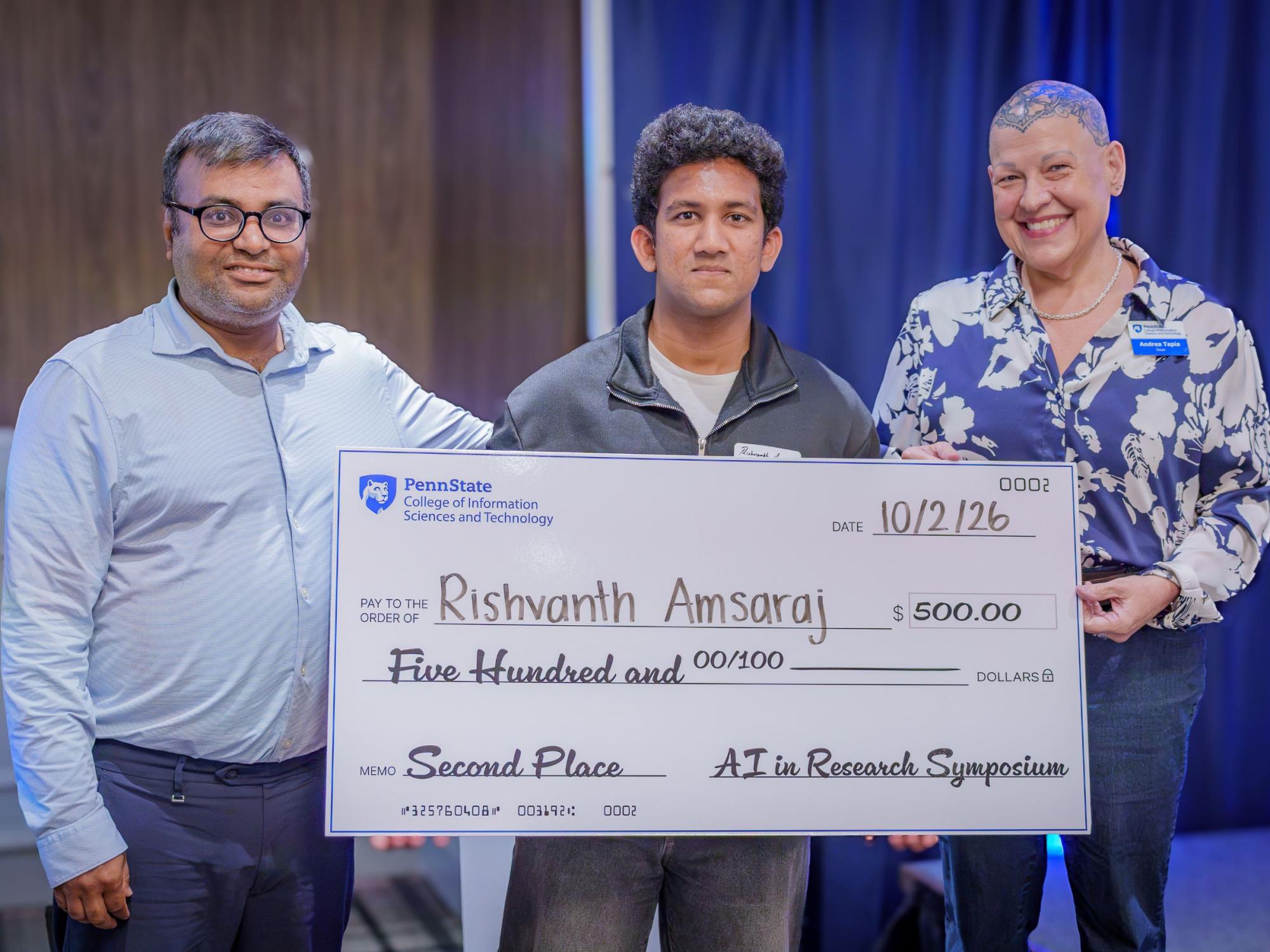 three smiling people hold giant five-hundred dollar check