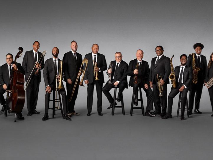 A variety of musicians stand with their instruments for a portrait.