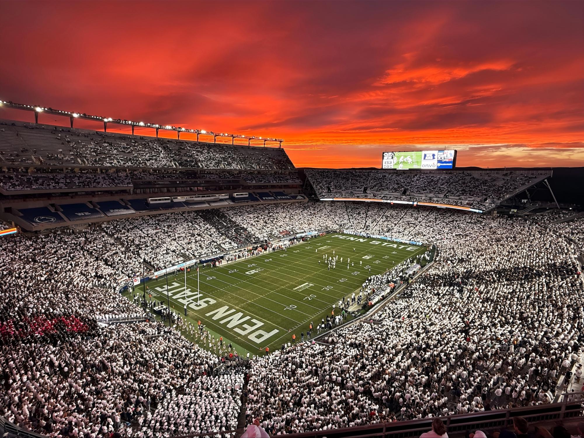 Vivid red sunset over a packed Beaver Stadium during Homecoming football game.