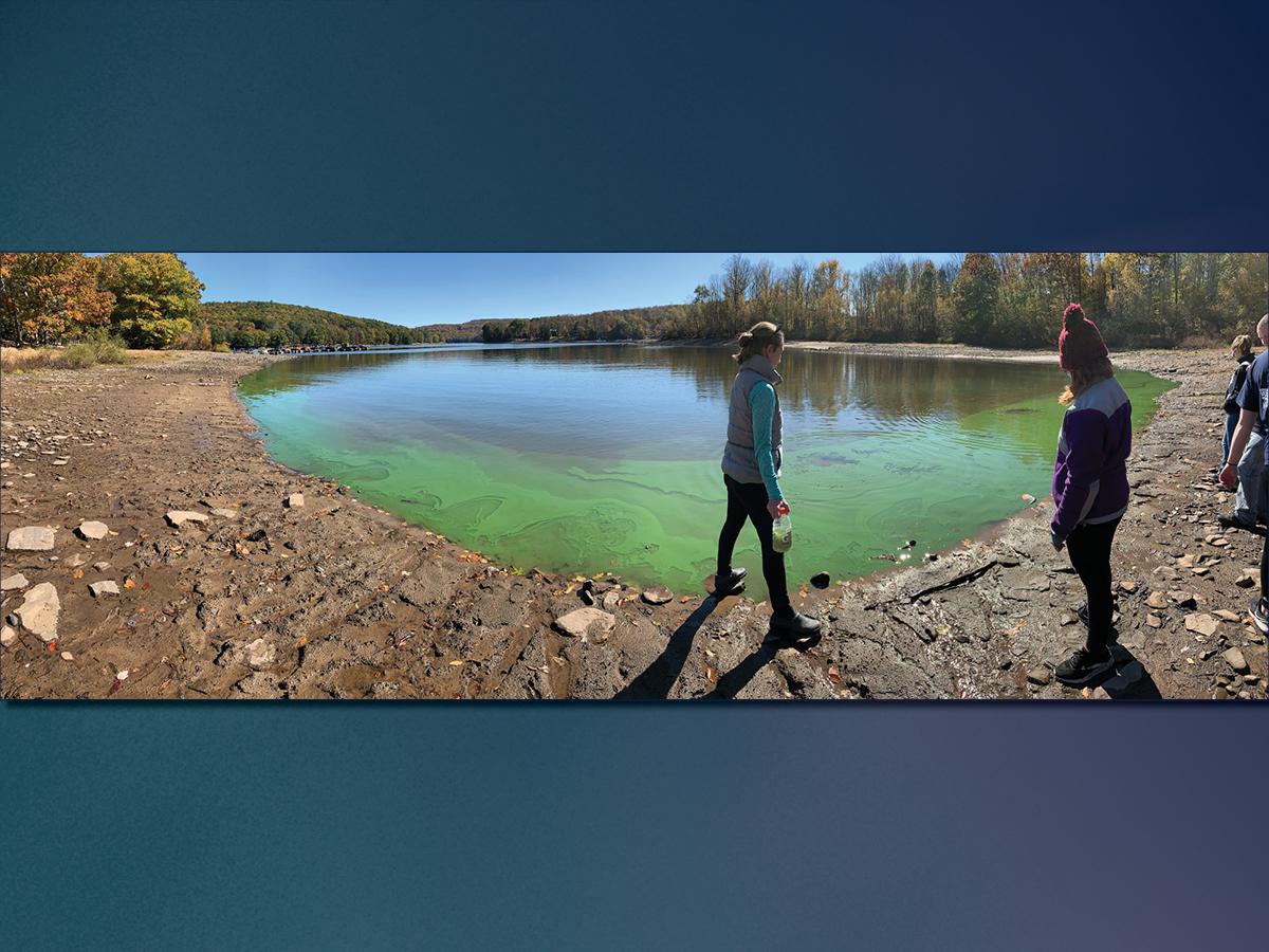 Sarah Princiotta and students stand in front of lake filled with cyanobacteria