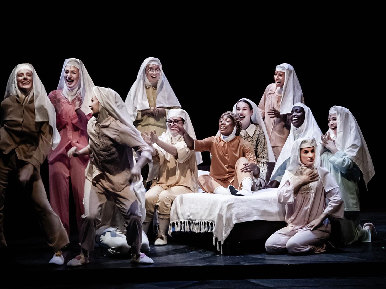 A group of performers dressed as nuns in pajamas singing on stage
