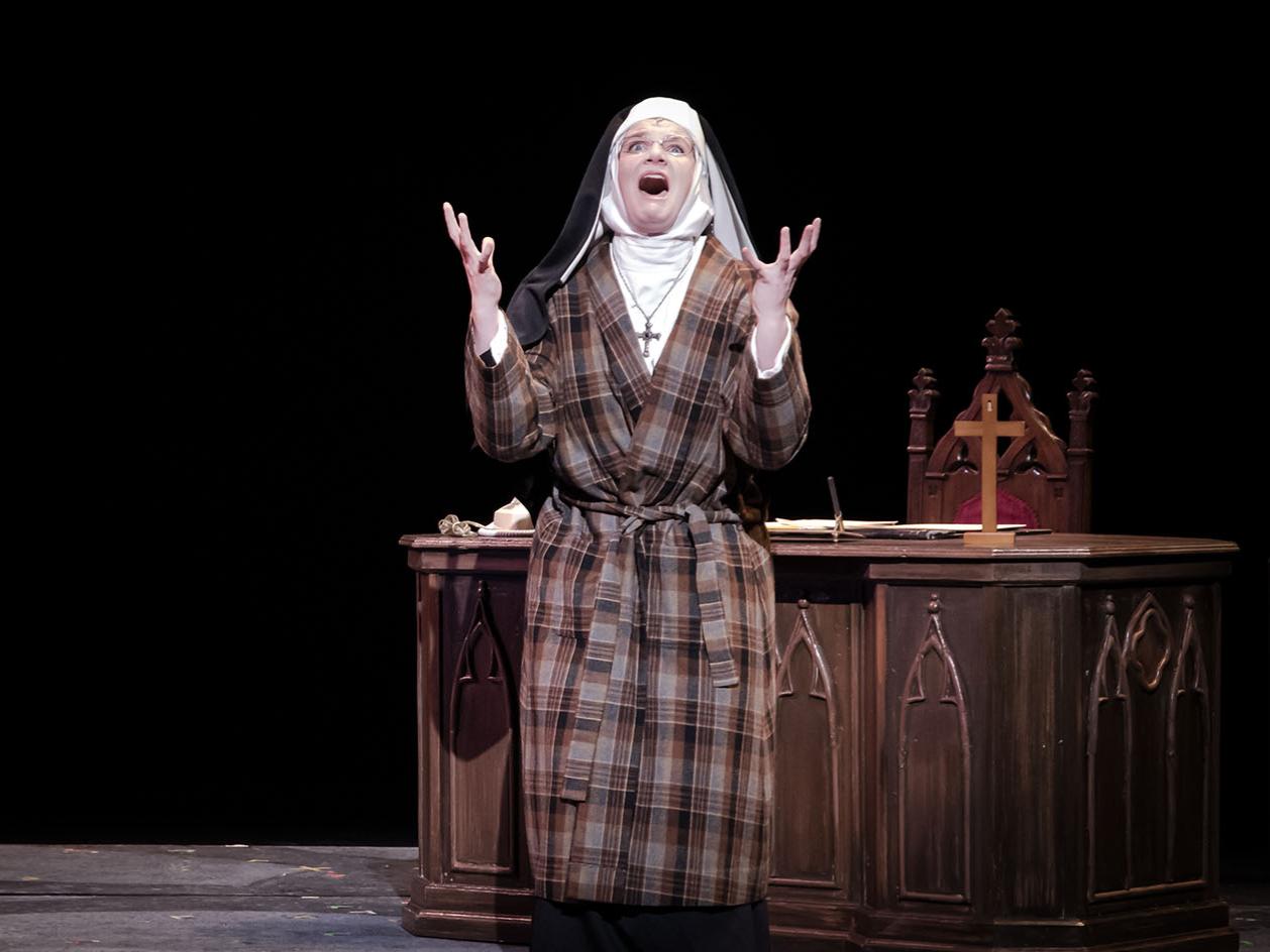 A performer dressed as a nun sings alone in a church