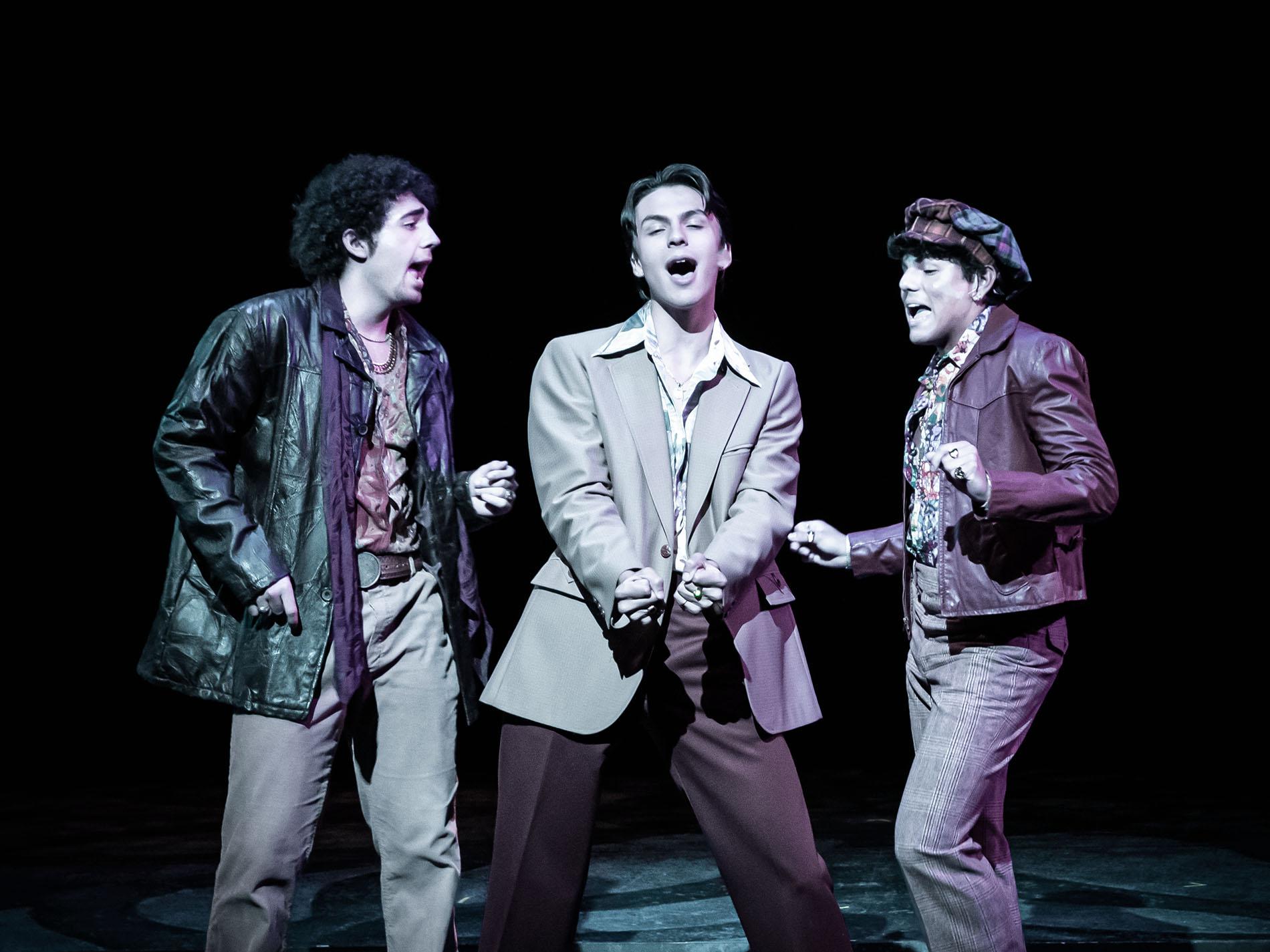 Three performers singing on stage