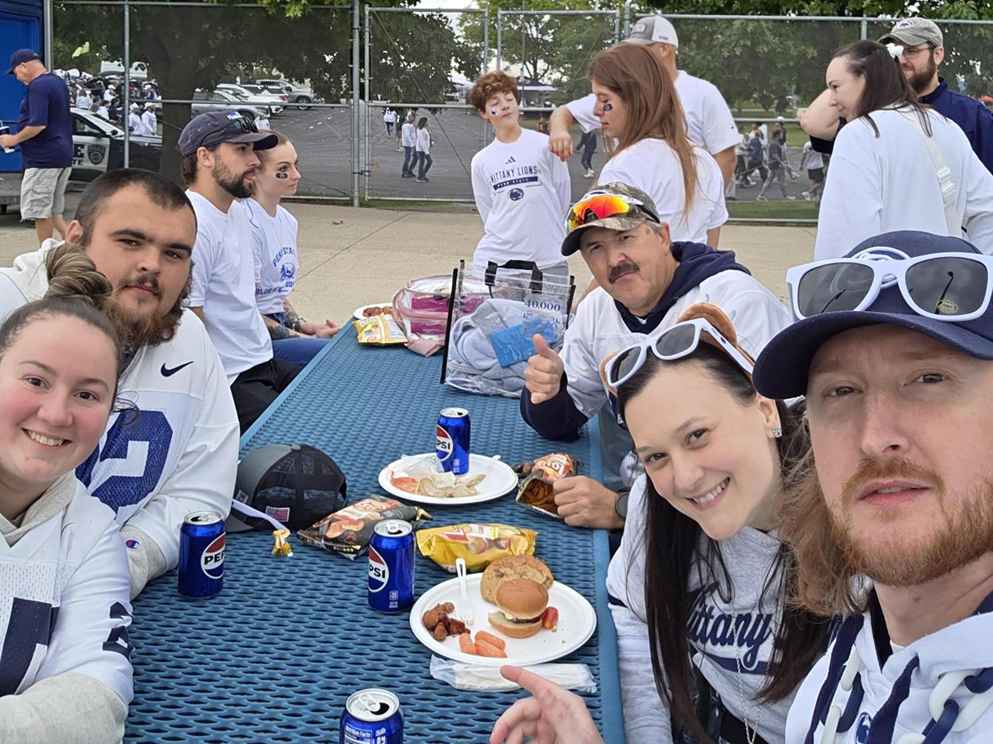 A group of people eating at a picnic table.