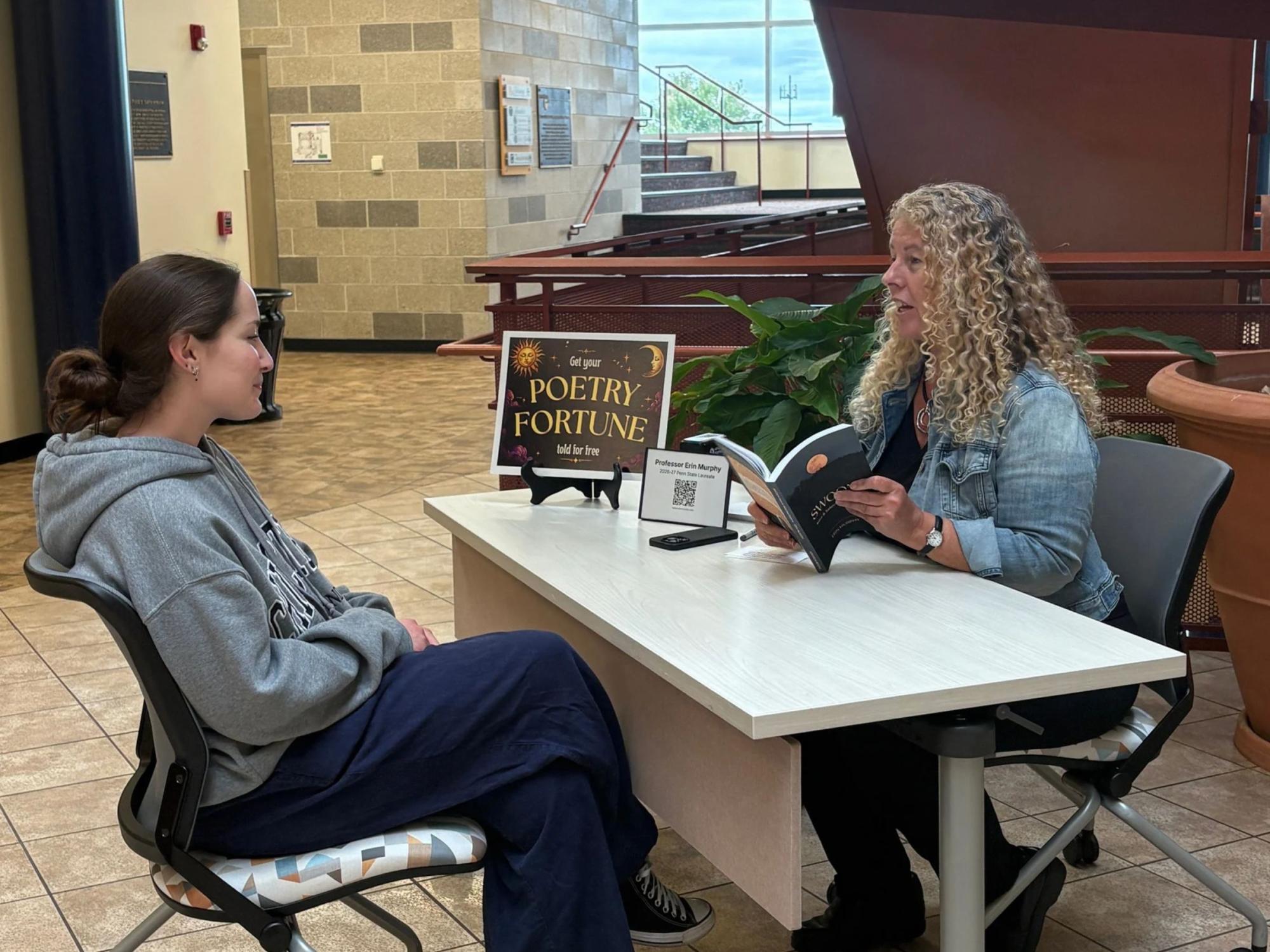 Penn State Laureate Erin Murphy reads a poetry fortune to a student seated across from her at a table in the Penn State York library.