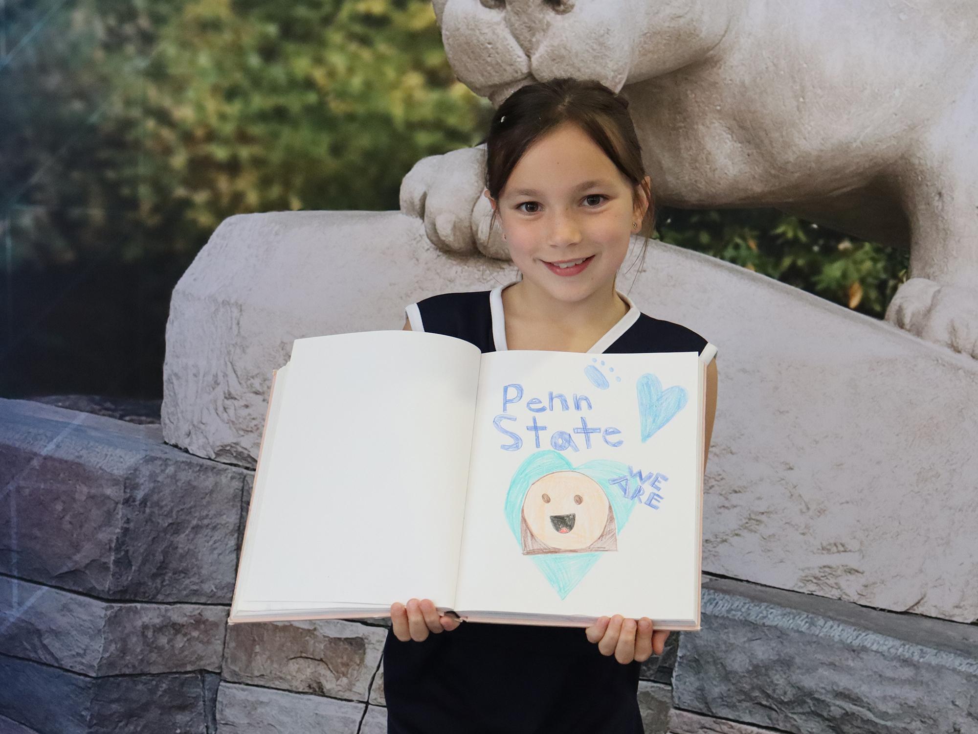 A girl holds a drawing of the Penn State Nittany Lion mascot.