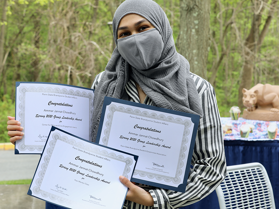 Female student sharing her three award certificates.