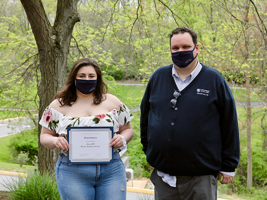 A student and her supervisor sharing her award certificate.