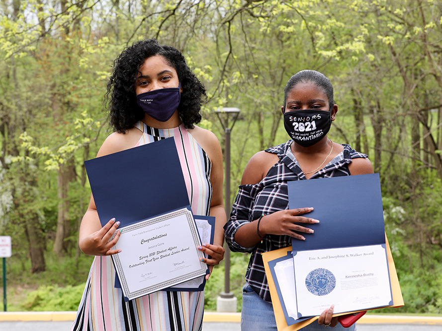 Two female students sharing their award certificates.
