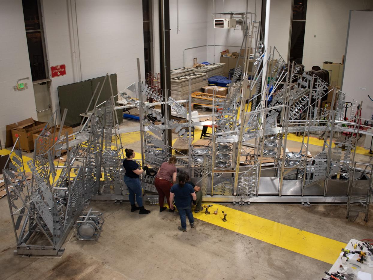 Three students assemble pieces of the metal structure in the Laundry Building