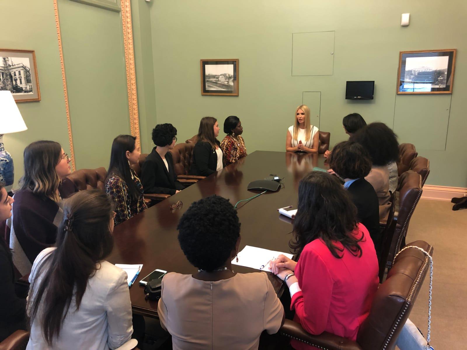 A dozen women sitting around a table. 