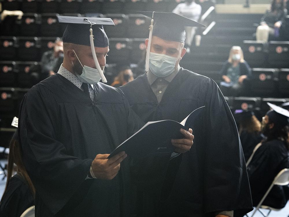Graduates look over the commencement program