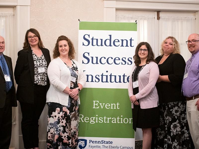 A group of people pose before a sign that reads "Student Success Institute."