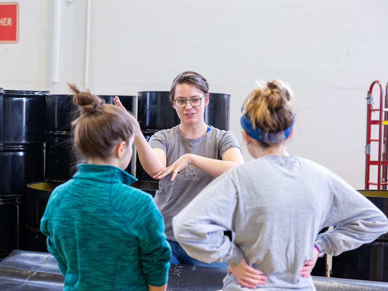 One female research assistant instructs two other female undergraduate students how to assemble parts of the chapel.