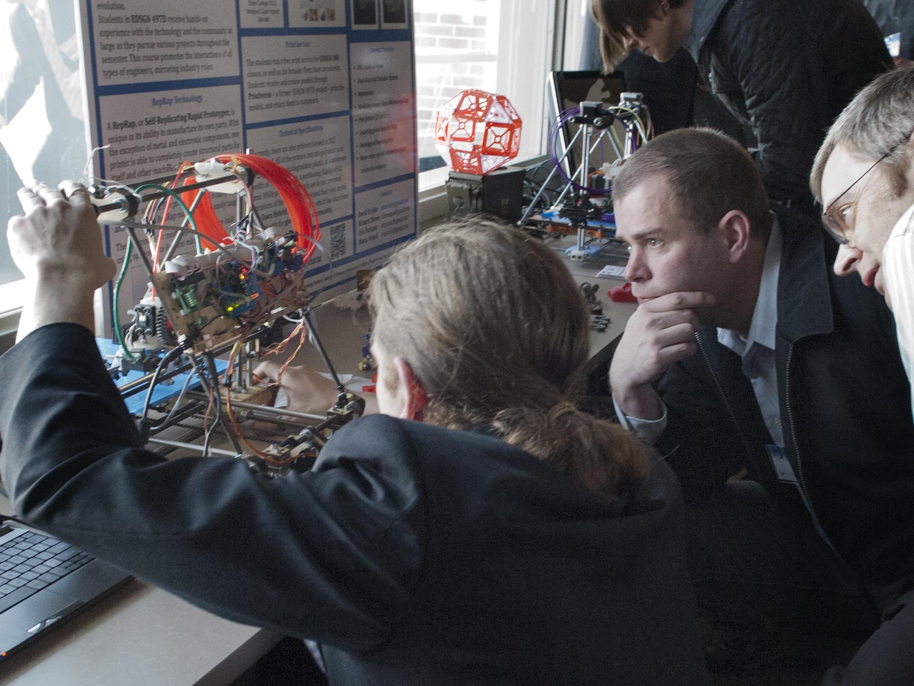 Tech showcase participants study 3-D printer