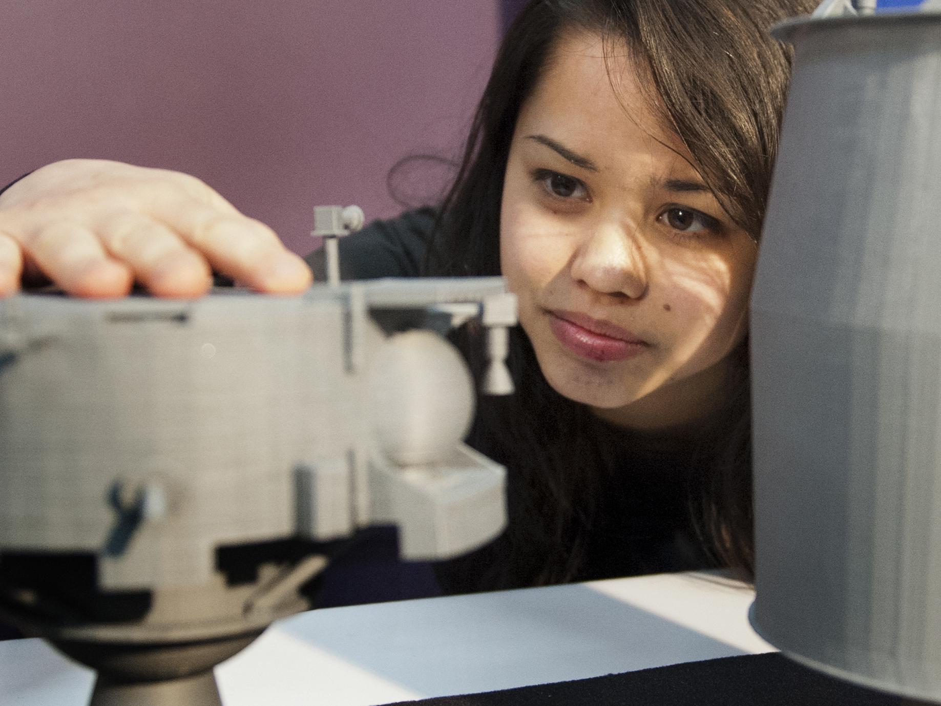 Kara Morgan looking at a 3-D printed model of a spacecraft