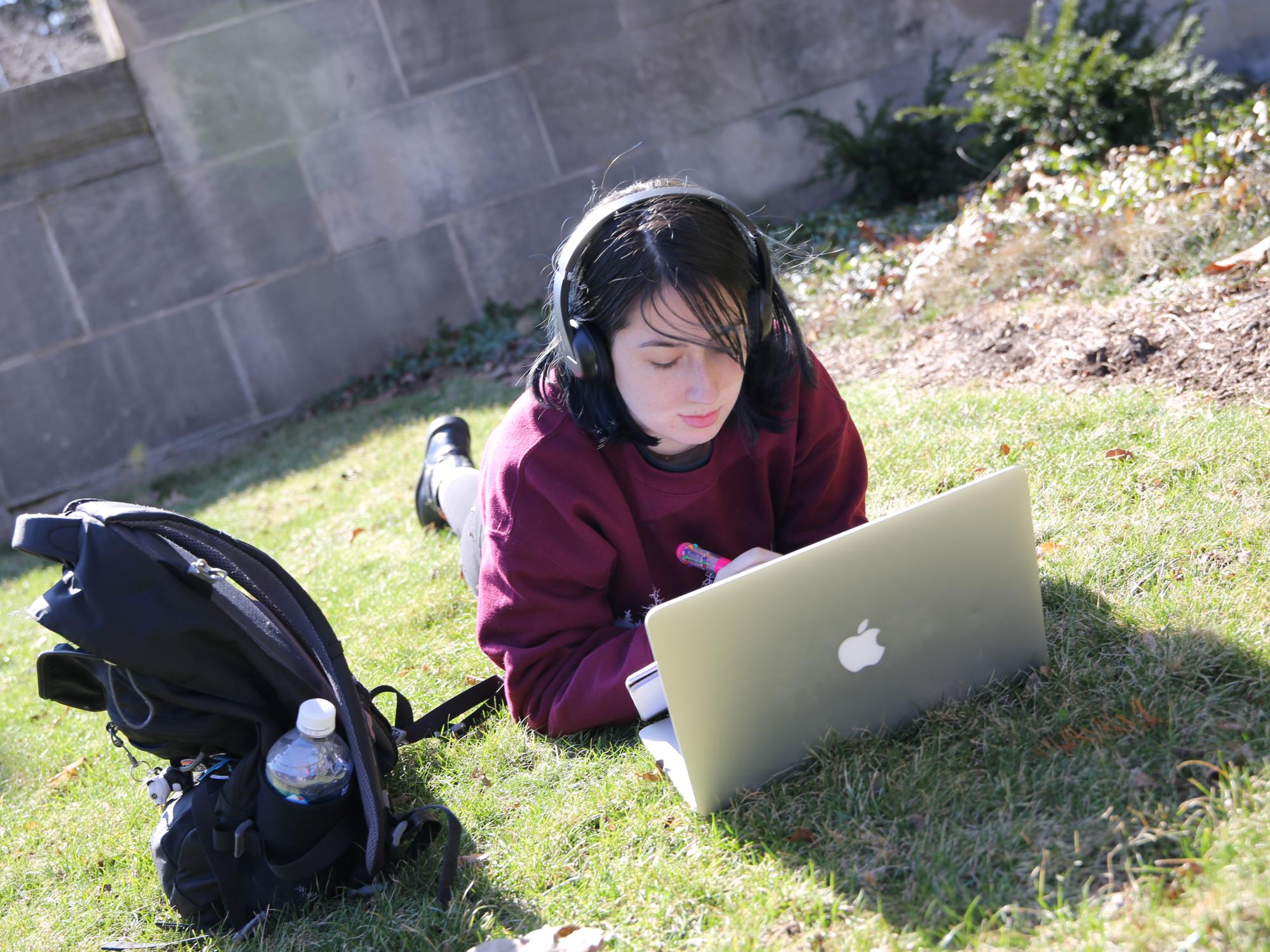 Student working on her online course assignment outside.