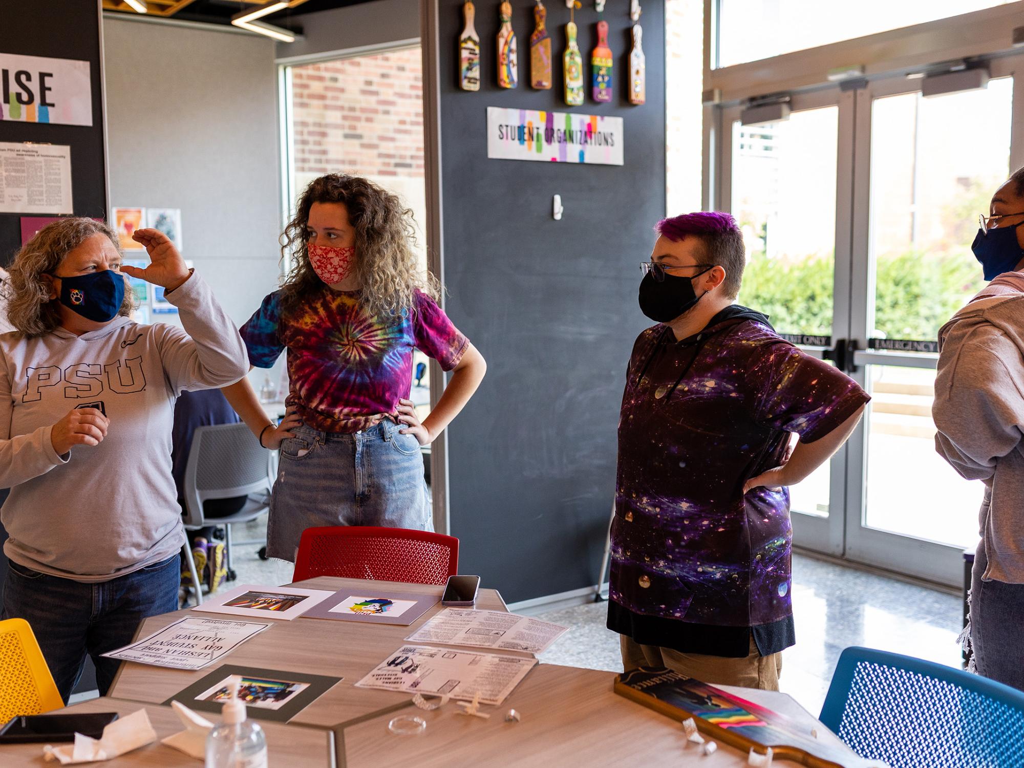 Four people standing around a table discuss how to put up an exhibit.