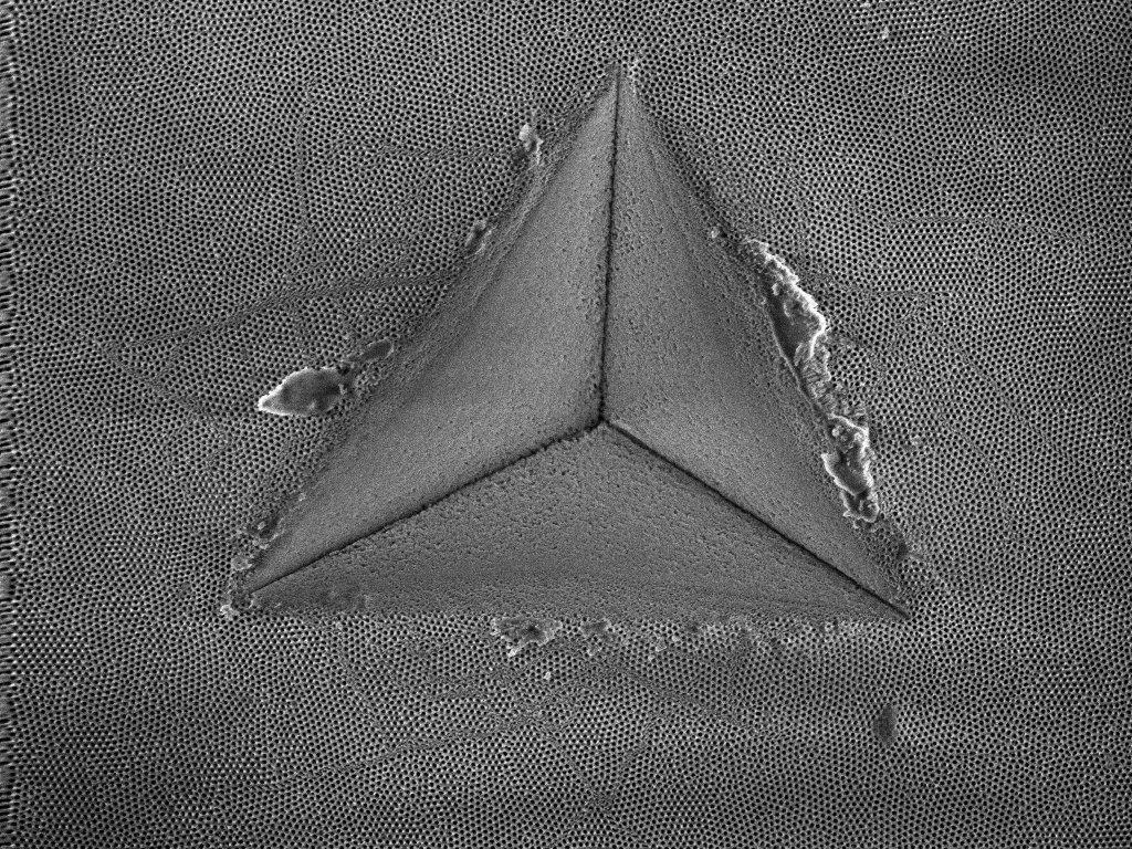 A nano-porous anodic aluminum oxide membrane after nanoindentation showing shear banding behavior around an indentation impression.