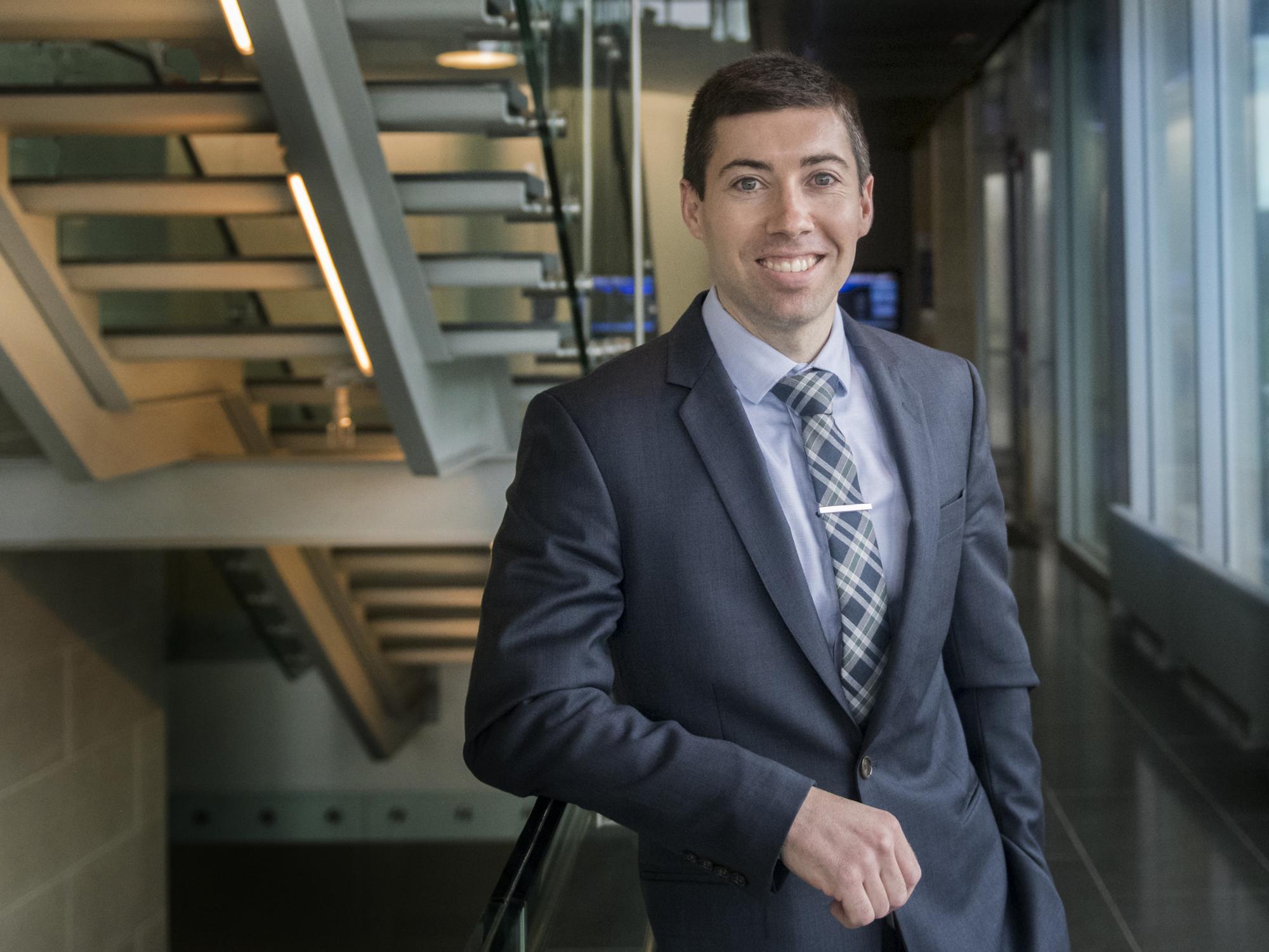 Portrait of Asher Rosinger standing in front of stairs
