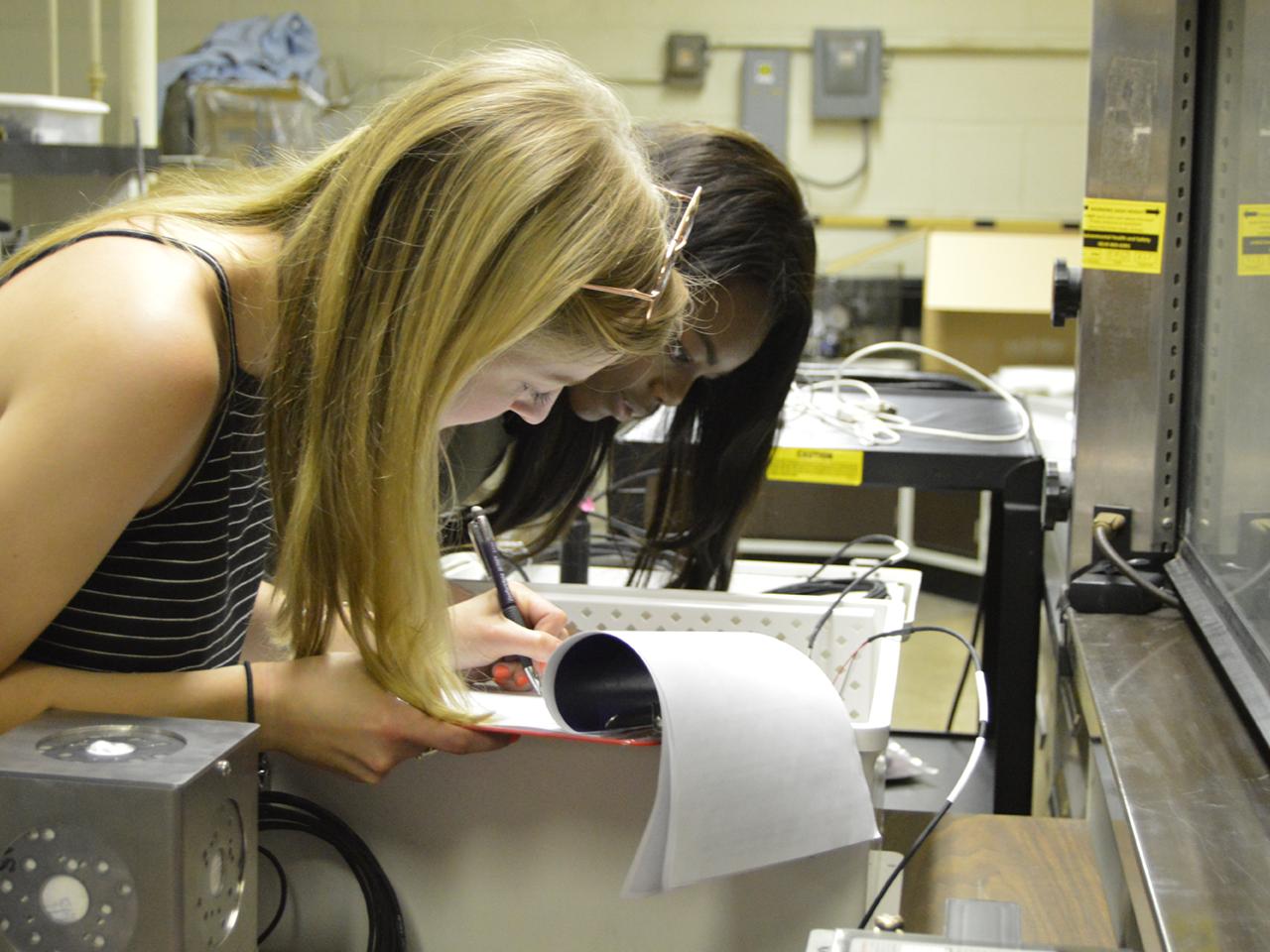 Energy engineering students Worlasie Djameh and Corryn Klien mark down the location of wires used to transmit information in the All-Seeing Eye device.